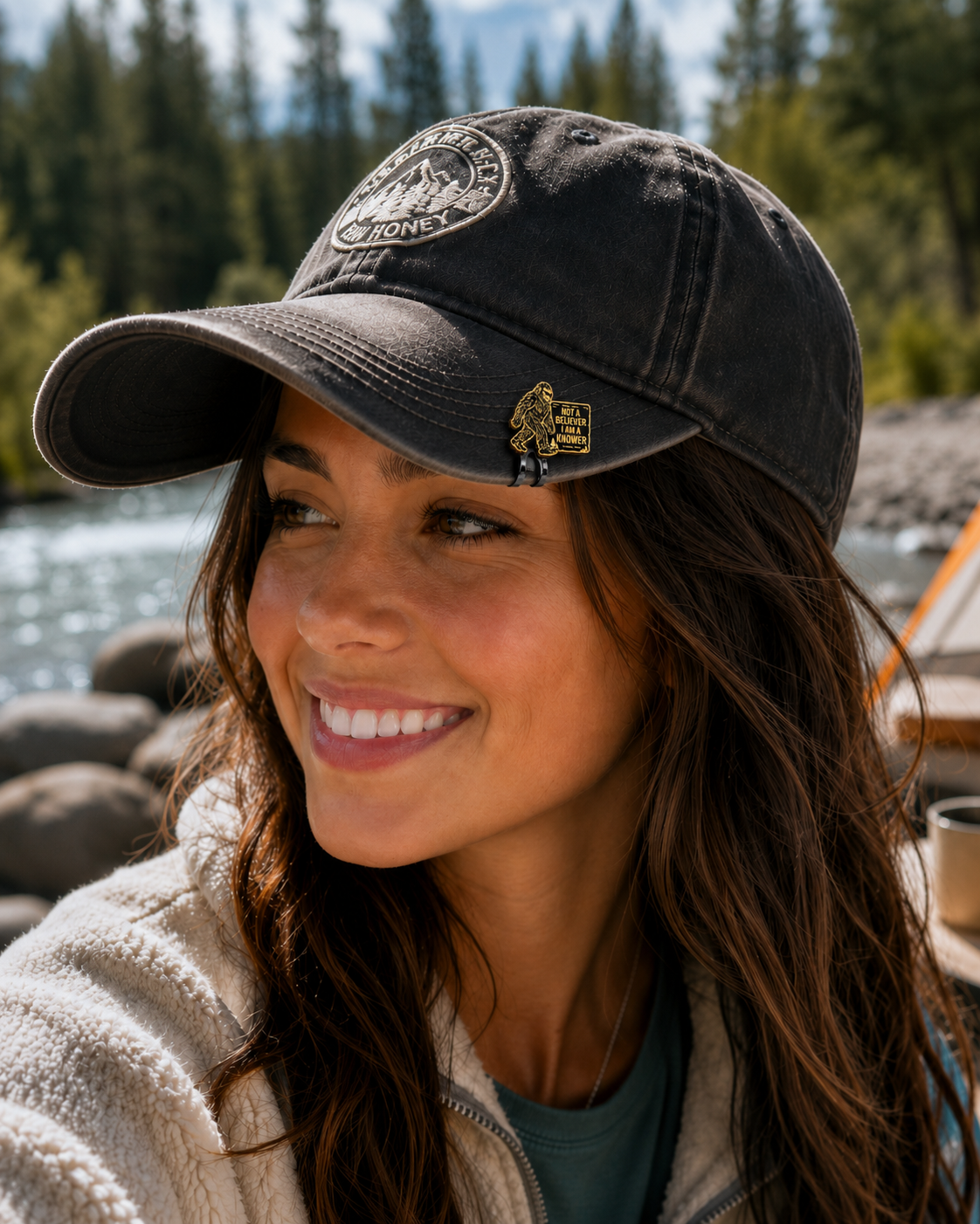 Woman wearing a Bigfoot Knower Hat Clip on a black outdoor hat while camping