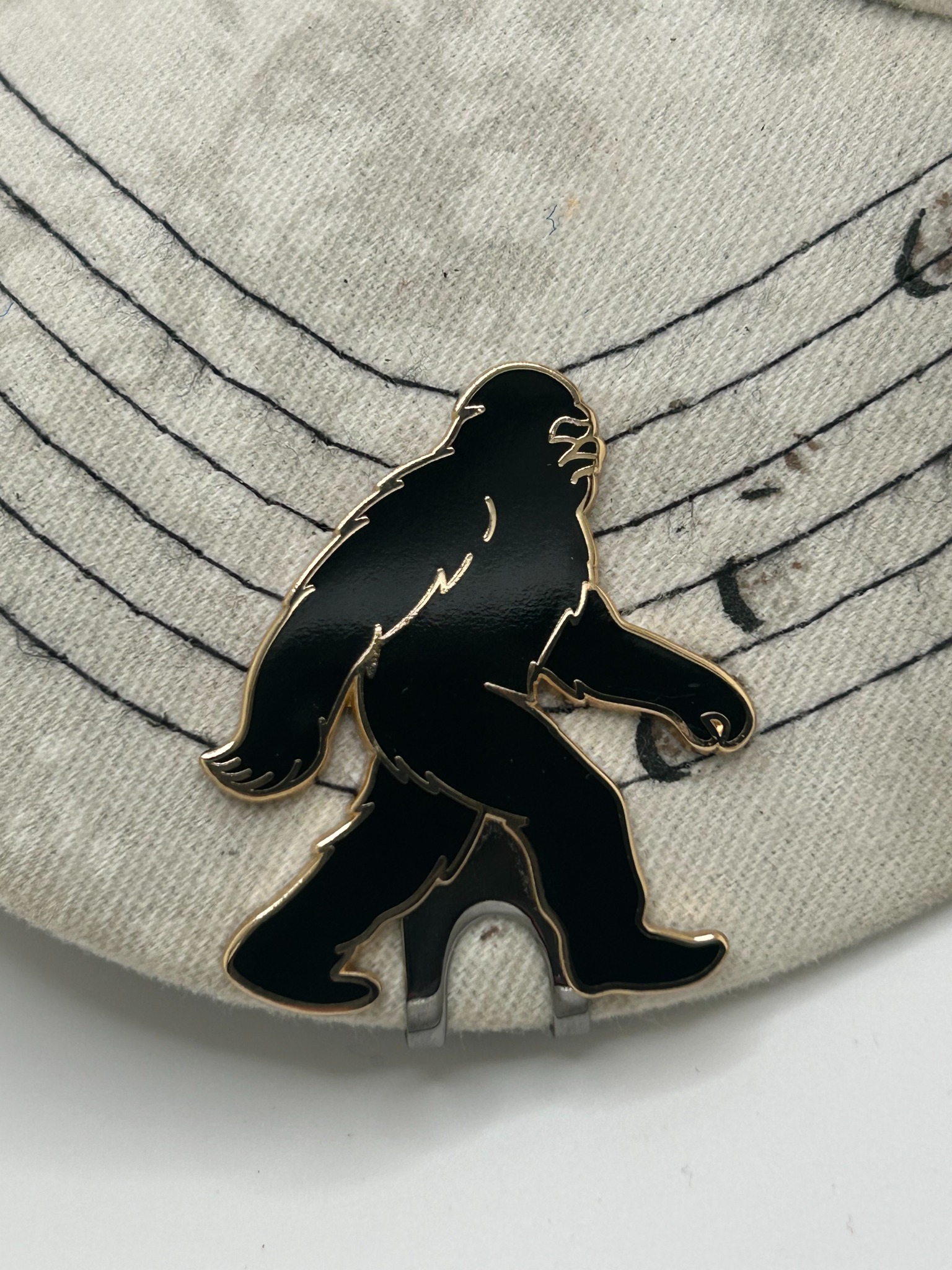 Close-up of Bigfoot Walker hat clip attached to white hat brim